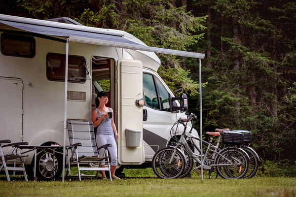 Woman is standing with a mug of coffee near the camper RV.