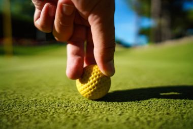 Gün batımında yeşil çimenlerin üzerinde Mini Golf sarı top