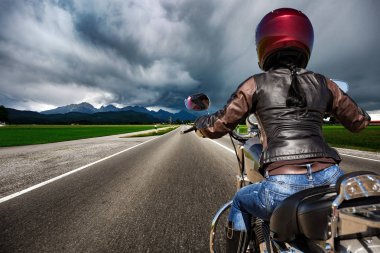 Biker girl on a motorcycle hurtling down the road in a lightning clipart