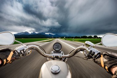 Biker on a motorcycle hurtling down the road in a lightning stor clipart