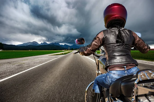 Байкерша на мотоцикле мчится по дороге в молнии — стоковое фото
