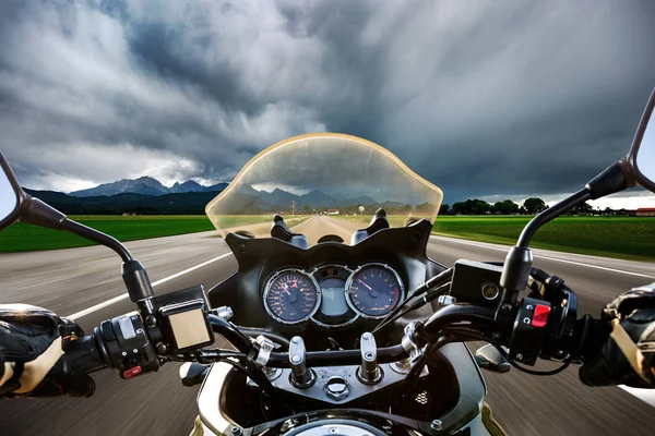 Fietser op een motorfiets op de weg in een bliksem stor raast — Stockfoto