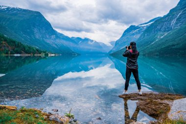 Nature photographer tourist with camera shoots lovatnet lake Bea clipart