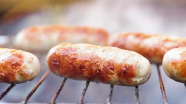 Izgarada ateşte pişmiş lezzetli sulu sosisler.