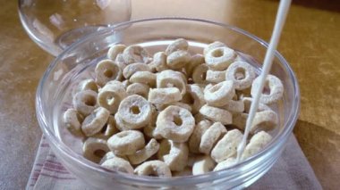 Sabah kahvaltısı için kâsede gevrek yulaf gevreği ve süt. Döndürme izleyici çekimi ile yavaş çekim.