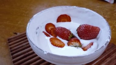 Çilekler çırpılmış krema kasesine düşüyorlar. Dönüşümlü çekim ile ağır çekim..