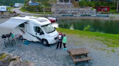 Bir çift, kameralı bir dronla fotoğraf çekiyor. Güzel Doğa Norveç doğal manzarası. Rahatlamak için kamp alanının havadan görüntüsü. Aile seyahati, karavanla tatil gezisi..