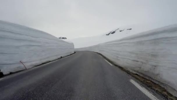 Condução de um carro em uma estrada de montanha na Noruega com parede de neve alta — Vídeo de Stock