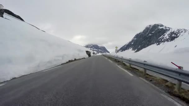 雪の壁が高いノルウェーの山岳道路で車を運転する — ストック動画