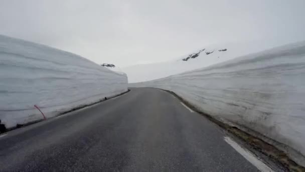 Condução de um carro em uma estrada de montanha na Noruega com parede de neve alta — Vídeo de Stock