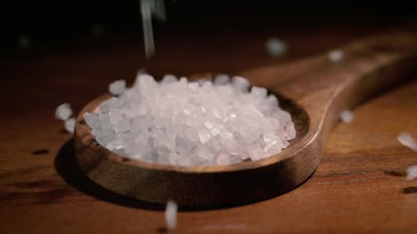 Mořská sůl krystaly detailní up v dřevěné lžíce na kuchyňském stole. — Stock video