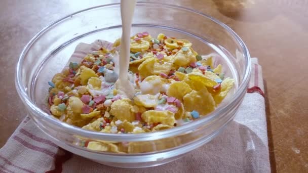 Knusprige gelbe Cornflakes in die Schüssel für ein leckeres Frühstück mit Milch. Zeitlupe mit Drehverfolgungsschuss. — Stockvideo