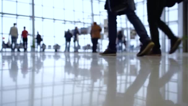 People out of focus walk inside a bright, modern building. Focus in the foreground — Stock Video