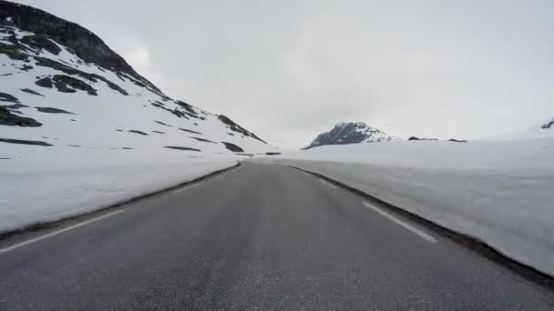 Condução de um carro em uma estrada de montanha na Noruega com parede de neve alta — Vídeo de Stock