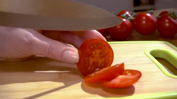 Cuchillo corta tomate en tablero de madera de cámara lenta con disparo de seguimiento de rotación . — Vídeo de stock