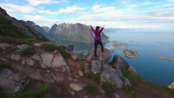 Hiker kvinna står med händerna upp uppnå toppen. Lofoten öar är en skärgård i Nordland, Norge. — Stockvideo