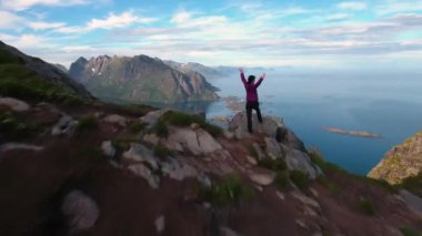Yürüyüş yapan kadın ellerini kaldırdı ve zirveye ulaştı. Lofoten Adaları Norveç 'in Nordland eyaletinde yer alan bir takımadalardır..