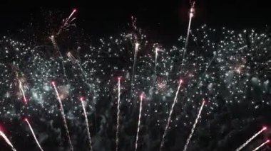 Gece gökyüzünde renkli havai fişekler patlıyor. Kutlamalar ve olaylar parlak renklerle.