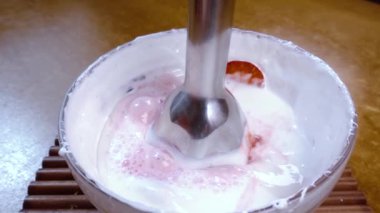 Karıştırıcı kullanarak çırpılmış yumurta ve çilek. Döndürme izleyici çekimi ile yavaş çekim.