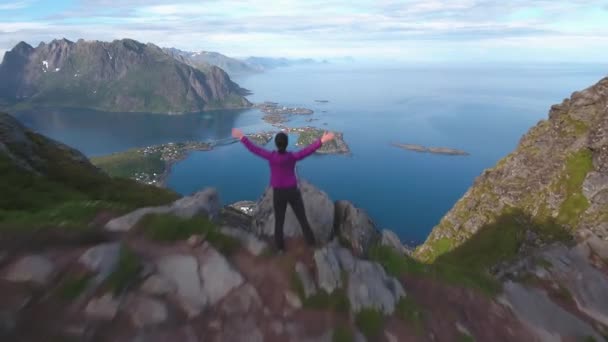 Mujer excursionista de pie con las manos en alto logrando la cima. Islas Lofoten es un archipiélago en el condado de Nordland, Noruega. . — Vídeos de Stock