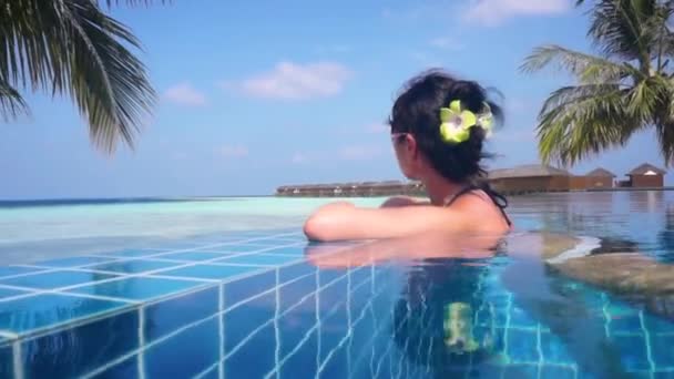 Menina olhando para o oceano enquanto sentado à beira da piscina — Vídeo de Stock