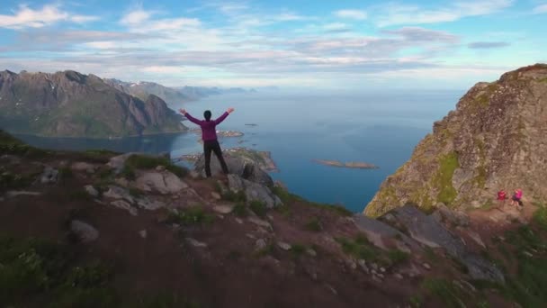 Yürüyüş yapan kadın ellerini kaldırdı ve zirveye ulaştı. Lofoten Adaları Norveç 'in Nordland eyaletinde yer alan bir takımadalardır.. — Stok video