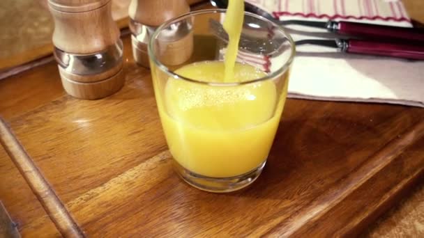 橙汁倒入一杯,早上吃早餐.旋转跟踪射击慢动作. — 图库视频影像