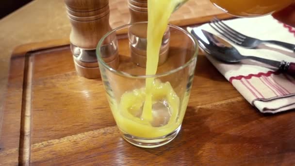 El jugo de naranja vertiendo en un vaso, el desayuno de la mañana. Movimiento lento con disparo de seguimiento de rotación . — Vídeos de Stock