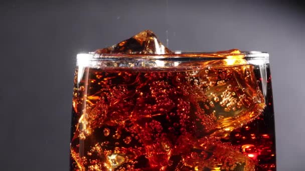 Cola con hielo y burbujas en vidrio de cámara lenta. — Vídeos de Stock