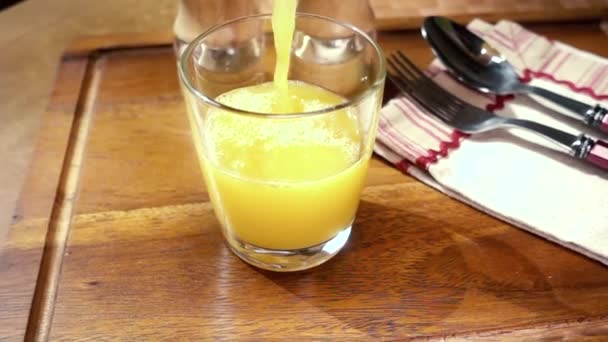 El jugo de naranja vertiendo en un vaso, el desayuno de la mañana. Movimiento lento con disparo de seguimiento de rotación . — Vídeos de Stock