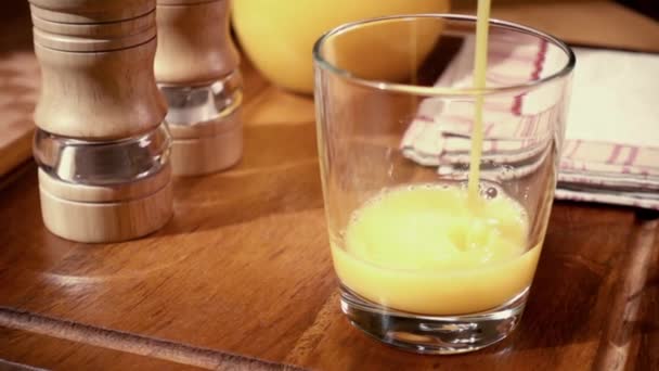 El jugo de naranja vertiendo en un vaso, el desayuno de la mañana. Movimiento lento con disparo de seguimiento de rotación . — Vídeos de Stock