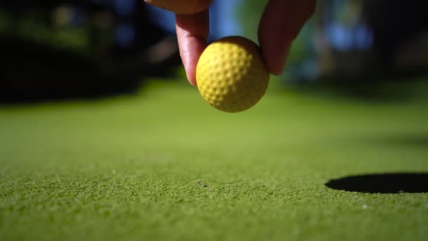 Mini Golf žlutý míč s pálkou v blízkosti otvoru při západu slunce — Stock video