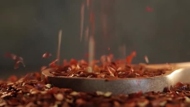 Piros csípős chili paprika pelyhek fa kanállal közelkép a konyhaasztalon. — Stock videók