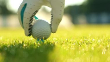 Eldiven takıp golf topuna vuruyor.