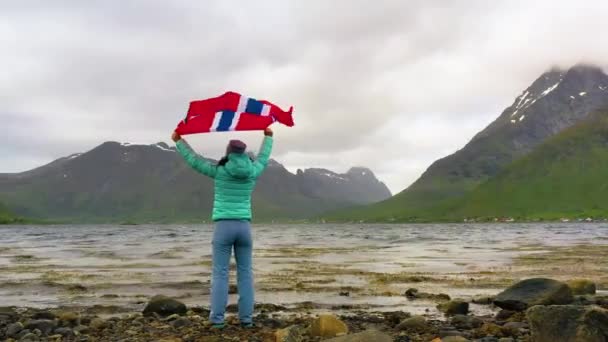 Mujer con una bandera ondeante de Noruega en el fondo de la naturaleza — Vídeos de Stock