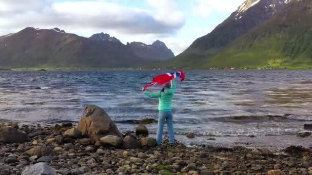 Vrouw met een wapperende vlag van Noorwegen op de achtergrond van de natuur — Stockvideo