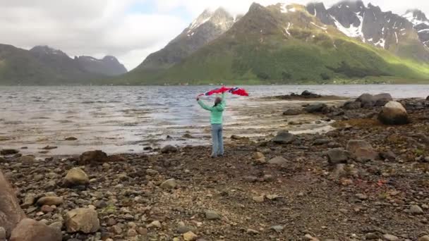 Vrouw met een wapperende vlag van Noorwegen op de achtergrond van de natuur — Stockvideo