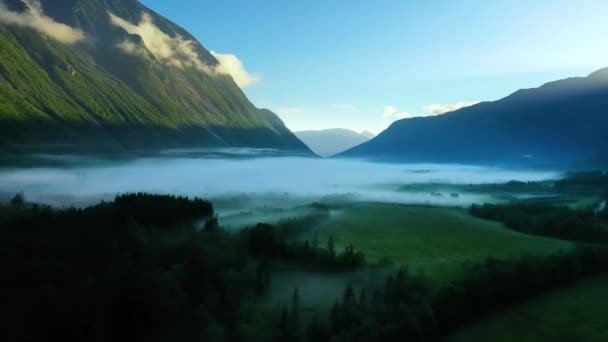 햇빛을 받는 산들 사이로 아침 안개가 골짜기를 덮고 있다. 안개와 노르웨이의 아름다운 항공 영상. — 비디오