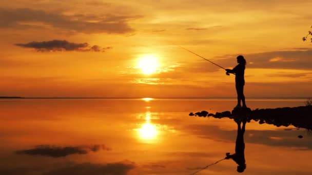 Woman fishing on Fishing rod spinning at sunset background. — Stock Video