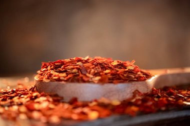 Ahşap kaşıkta kırmızı kırmızı kırmızı biber taneleri mutfak masasının üstünde..