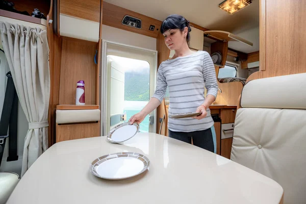 Woman cooking in camper, motorhome RV interior. Family vacation travel, holiday trip in motorhome, Caravan car Vacation.