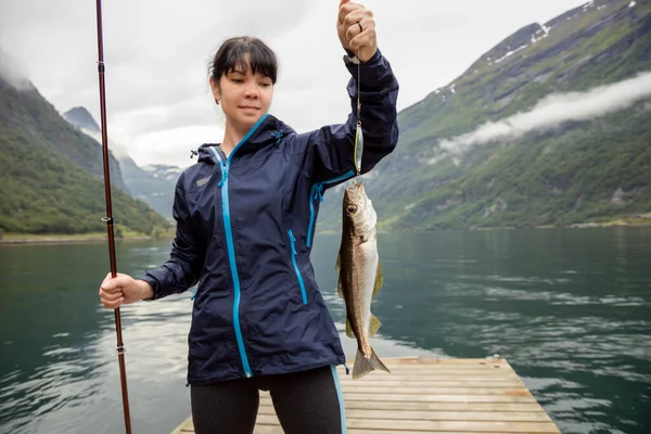 ノルウェーで回転する釣竿で釣りをする女性 ノルウェーでの釣りは地元のライフスタイルを受け入れる方法です 数え切れないほどの湖や川や広大な海岸線は素晴らしい機会を意味します — ストック写真