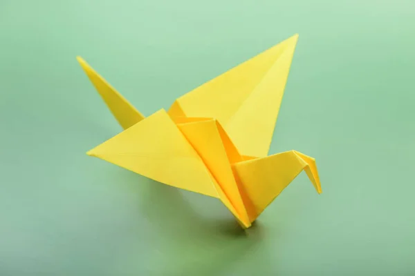 Origami fågel på grön bakgrund. Japansk vikbar papperssvan. — Stockfoto