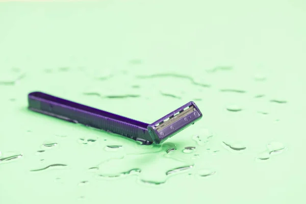 Shaving razor on wet pastel background Stock Picture