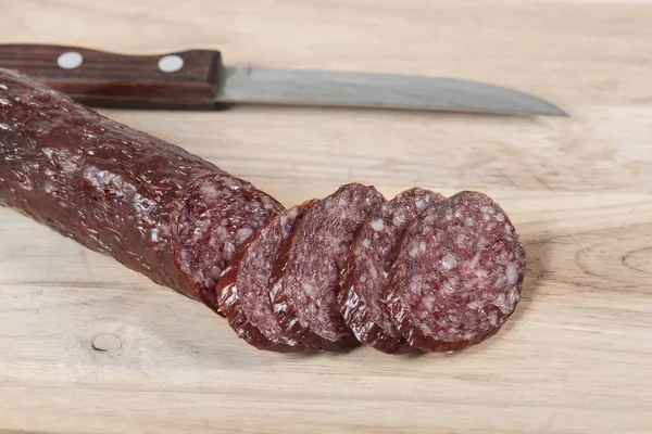 Torr salamikorv och kniv på träskiva med skivor — Stockfoto