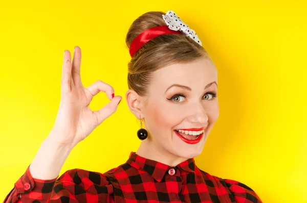 Glückliche junge Frau zeigt ok Zeichen mit den Fingern auf einem gelben Rücken — Stockfoto