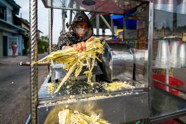 kadın bir road, Mitho, Vietnam yakınındaki bir taze kamışı suyu yapım