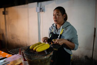 Kadın akşamları ana caddede mısır kızartıyor. Pai, Tayland.