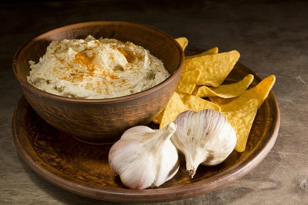 Hummus i en lergods maträtt och vitlök — Stockfoto