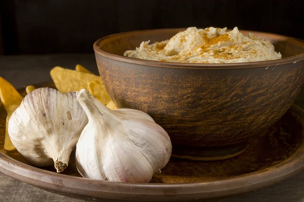 Hummus v kameninové misky a česnek — Stock fotografie